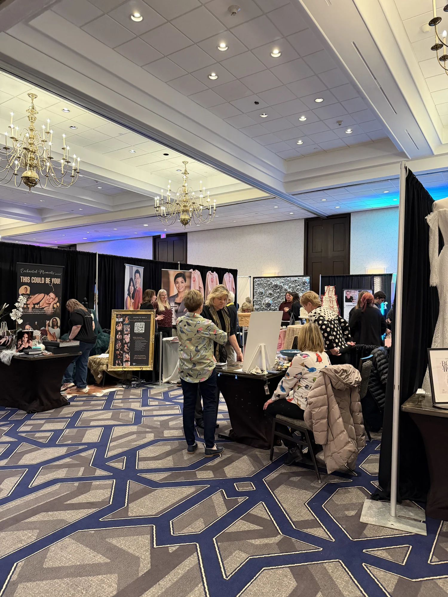 The ballroom at 24 Shelby Events filled with vendor booths under chandeliers