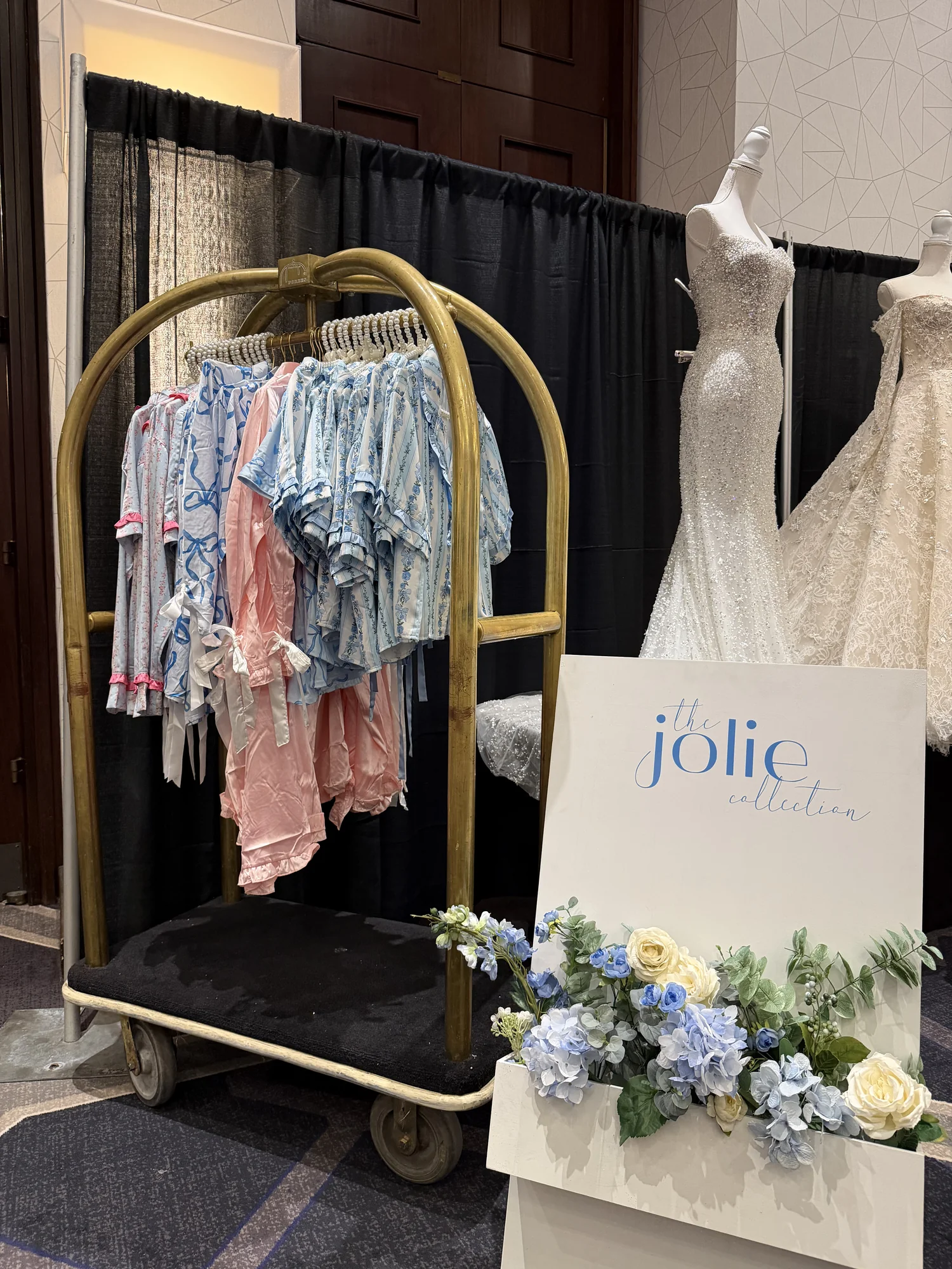 Jolie Collection display of blue and blush bridal party attire on a gold rack